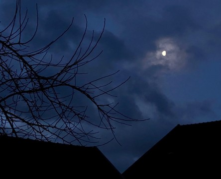 In der Dämmerung taucht der Mond zwischen den Wolken auf. 