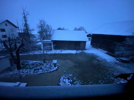 zwei Scheunen auf deren Dach Schnee liegt und der Boden zum großen Teil noch ohne Schnee ist im fahlen Morgenlicht 