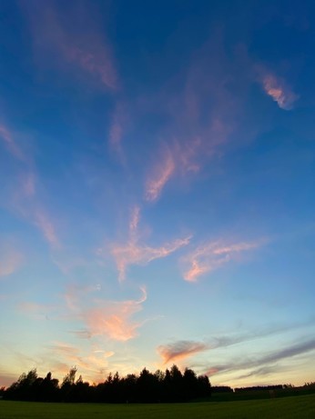Nach Sonnenuntergang werden nur ganz wenige Wolkenschleier am blauen Himmel leucht rosa angestrahlt 