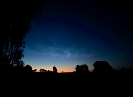 dunkelblauer Himmel und von unten schiebt sich eine bogenförmiger oranger Anteil rein 