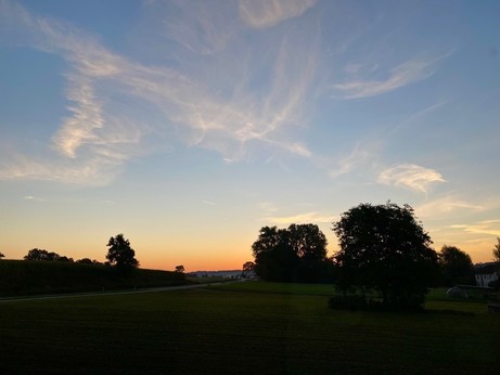 vor Sonnenaufgang ein oranger Streifen am Horizont und blauer Himmel mit ein paar Streifen drüber 