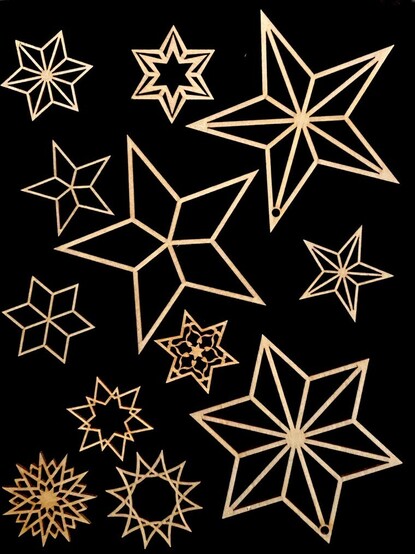 drei große und viele kleine Holzsterne in verschiedenen geometrischen Formen liegen auf einem schwarzen Untergrund 