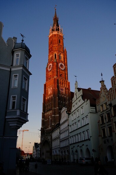 letzte schwache rötliche Sonnenstrahlen auf dem Turm der Backsteinkirche St. Martin von Landshut 