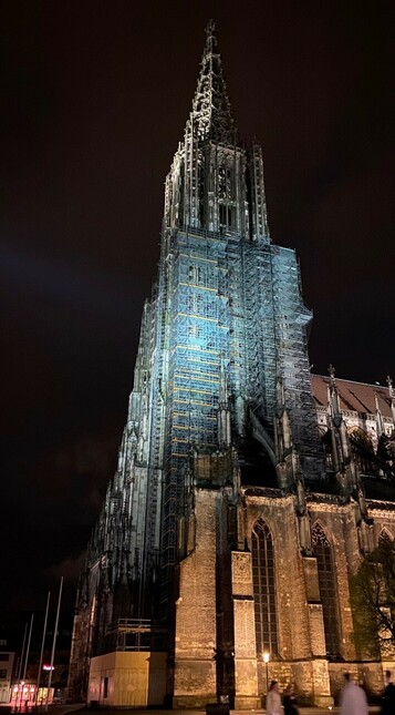 Nachtaufnahme des angestrahlten Turms vom Ulmer Münster mit Baugerüst