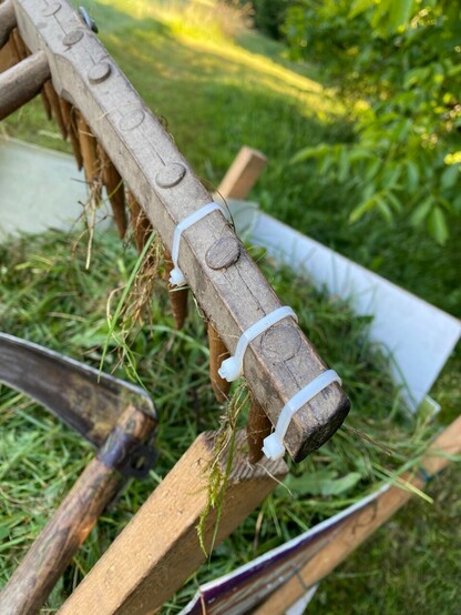 ein alter Holzrechen ist mit 3 kleinen Kabelbindern zusammen gebunden 