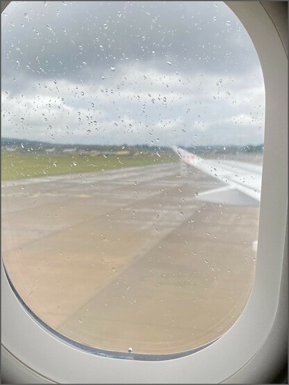 Regentropfen an der Scheibe eines Flugzeugs auf dem Flughafen 