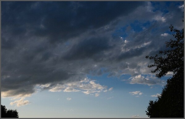 dunkle Wolken vor einem Himmel, der von hellblau nach strahlend blau nach oben rechts sich ändert 