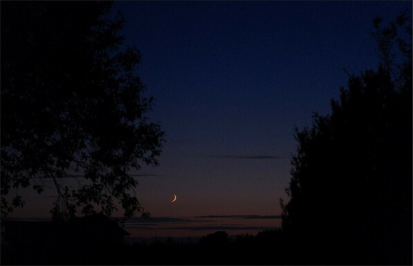 die Sonne ist schon länger verschwunden und eine eingefärbte Mondsichel hängt kurz überm Horizont 