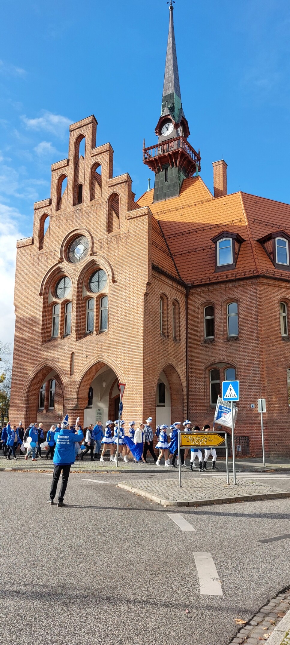 vor dem Rathaus Nauen marschieren die Mitglieder des Karnevalvereins in blau-weißen Kostümen