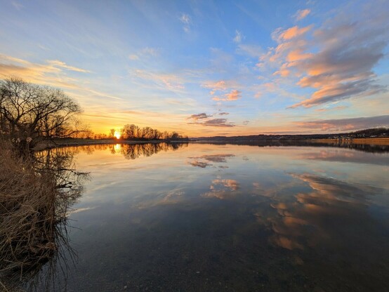 in einem See spiegelt sich der farbige Himmel vom Sonnenuntergang.