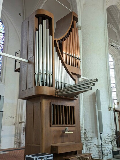 eine Orgel mit grauen und kupfernen Pfeifen. und einige Pfeifen ragen waagrecht über den Bedienplatz in den Raum