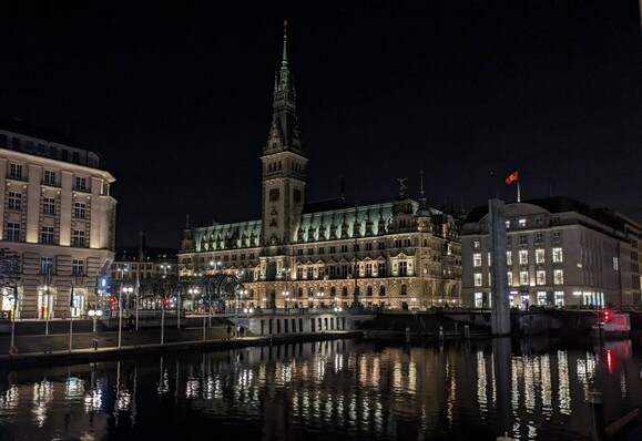 Spiegelung vom Hamburger Rathaus und anderen Gebäuden in der Nacht im Wasser