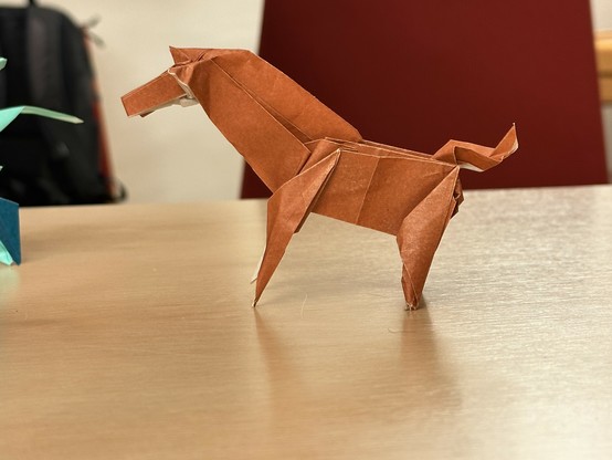 Ein in Origami Technik aus braunem Papier gefaltetes Tier das entfernt an ein Pferd erinnern kann. Oder an ein Urpferd. Oder ein Dinosaurier. Oder so etwas. 