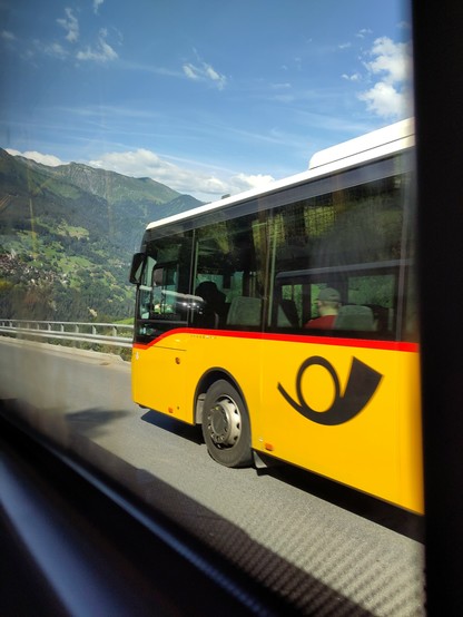 Foto. Ein gelber Bus auf einer Bergstrasse.