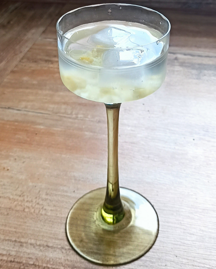 in einem schönen alten kleinen Weinglas mit grünem Fuß und Stiel die fertige Limonade, in der die Salzzitrone und die Eiswürfel schwimmen