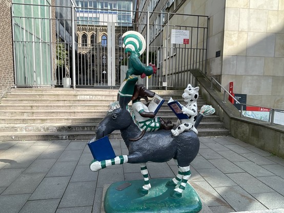 Skulptur mit einem Esel, einer Katze einem Hund, und einem Hahn, übereinander gestapelt im Sinne der Bremer Stadtmusikanten und jeweils mit Büchern in den Pfoten 