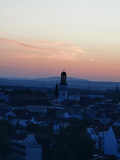 Kirchturm der 22 Apostelkirche in Frankenthal. Am Horizont der Donnersberg, die Stadt im Vordergrund liegt im Dunkeln.