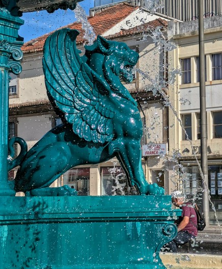 ein grünblauer geflügelter Löwe an einem Brunnen 