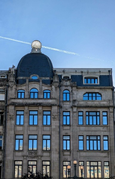 oben auf einem mehrstöckigen Haus ist eine gläserne Kugel, die von der Sonne durchleuchtet ist 