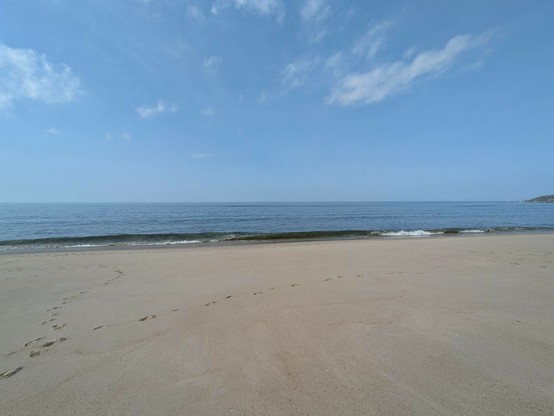 Sandstrand, blauer Himmel und sanfte Wellen 