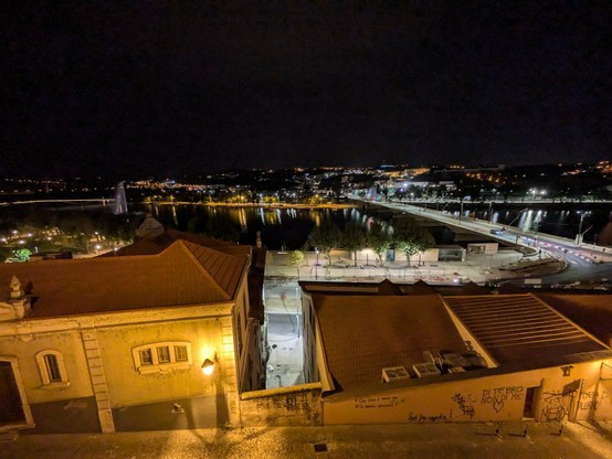 Blick von oben nachts auf die beleuchtete Stadt Coimbra und den Fluss 