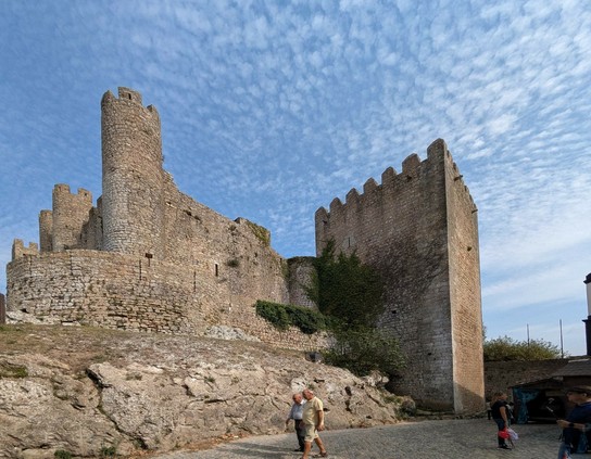 ein eckiger und mehrere rund Türme einer Burg stehen auf Fels