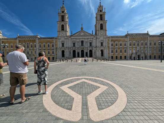 im Pflaster ist das Logo vom Weltkulturerbe eingelegt und dahinter die extrem breite Gebäudefront vom portugiesischen Nationalpalast 