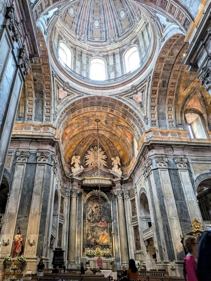 das Innere einer großen Kirche mit einer großen Kuppel und hellem, blauem und gelbem Marmor. Von oben kommt viel Licht