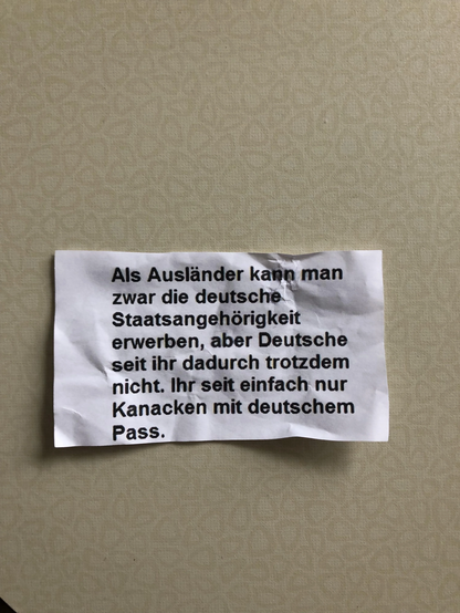 Zettel mit Aufschrift: "Als Ausländer kann man zwar die deutsche Staatsangehörigkeit erwerben, aber Deutsche seit ihr dadurch trotzdem nicht. Ihr yeit einfach nur Kanacken mit deutschem Pass."