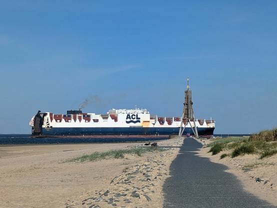 Hinter der Kugelbake fährt ein großes Frachtschiff Elbe aufwärts 