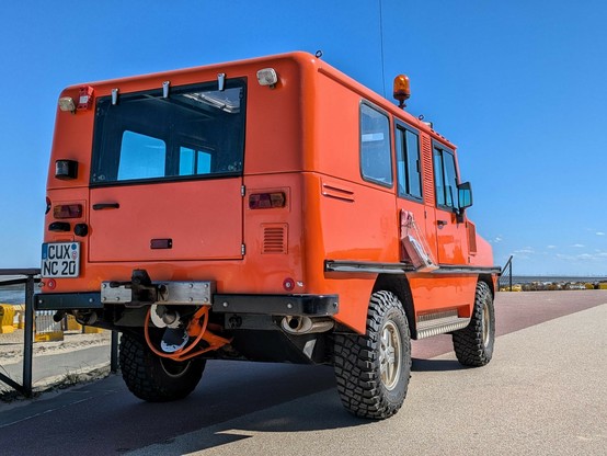 ein oranges Allraddauto von rechts unten fotografiert, damit die Schiffsschraube am Heck zu erkennen ist.
