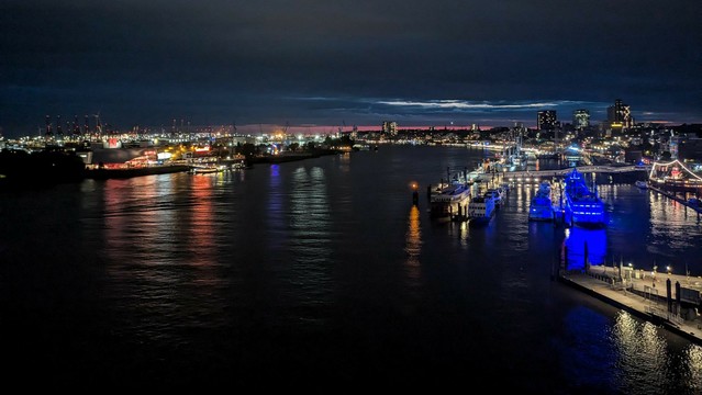 Lichter von Hafen und Stadt Hamburg von oben. Am Horizont noch letzte rote Schimmer vom Sonnenuntergang 