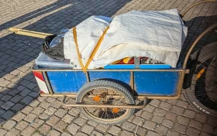 Fahrradanhänger, gefüllt mit Material, das mit einer Plane bedeckt ist
