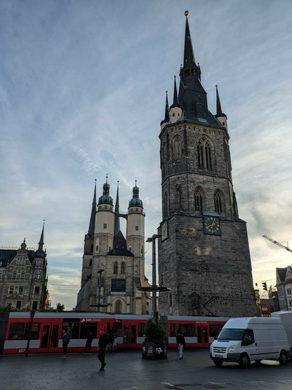 Blick vom Marktplatz auf einen steinernen Turm und große Kirche dahinter 