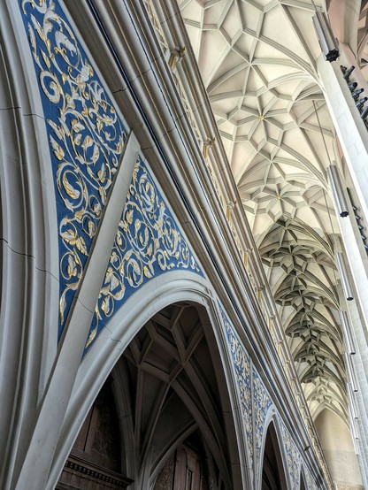 blau hinterlegte Verzierungen an der Wand und Blick zur Strebendecke