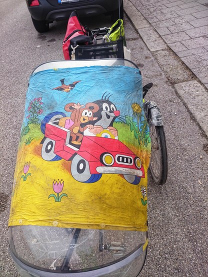 ein Kopfkissenbezug mit dem gezeichnetn tschechischen Maulwurf und anderen Tieren in einem Auto über den Wind- und Regenschutz gespannt 