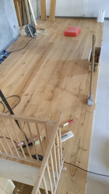 Ein großes Zimmer. Der Estrichboden ist sichtbar, fast die Hälfte des Bodens ist mit Holzdielen belegt.