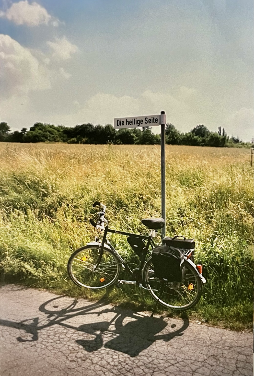 Mein Fahrrad parkt am Rande eines Kornfelds vor dem Straßenschild mit den merkwürdigen Namen