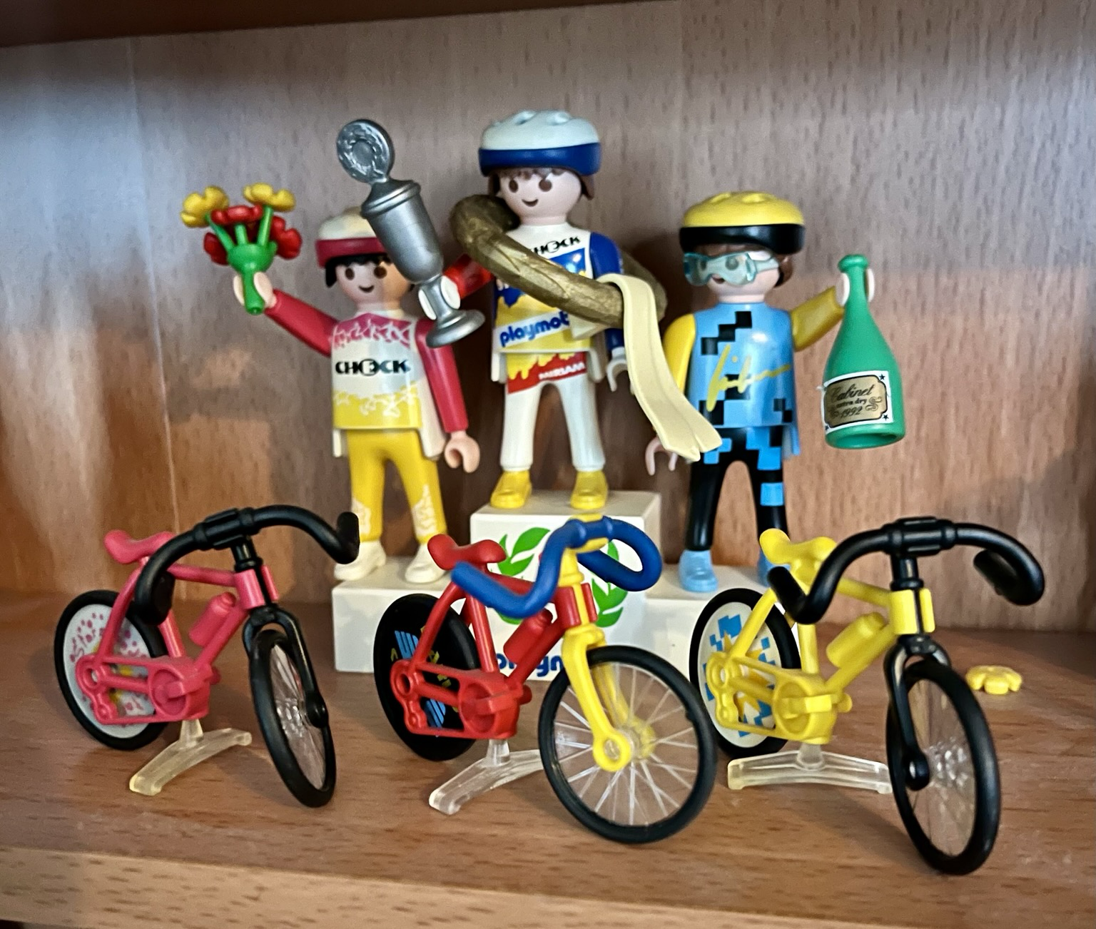 Siegerehrung nach einem Radrennen. Die Sieger stehen auf dem Siegerpotest. Davor stehen ihre drei Fahrräder.