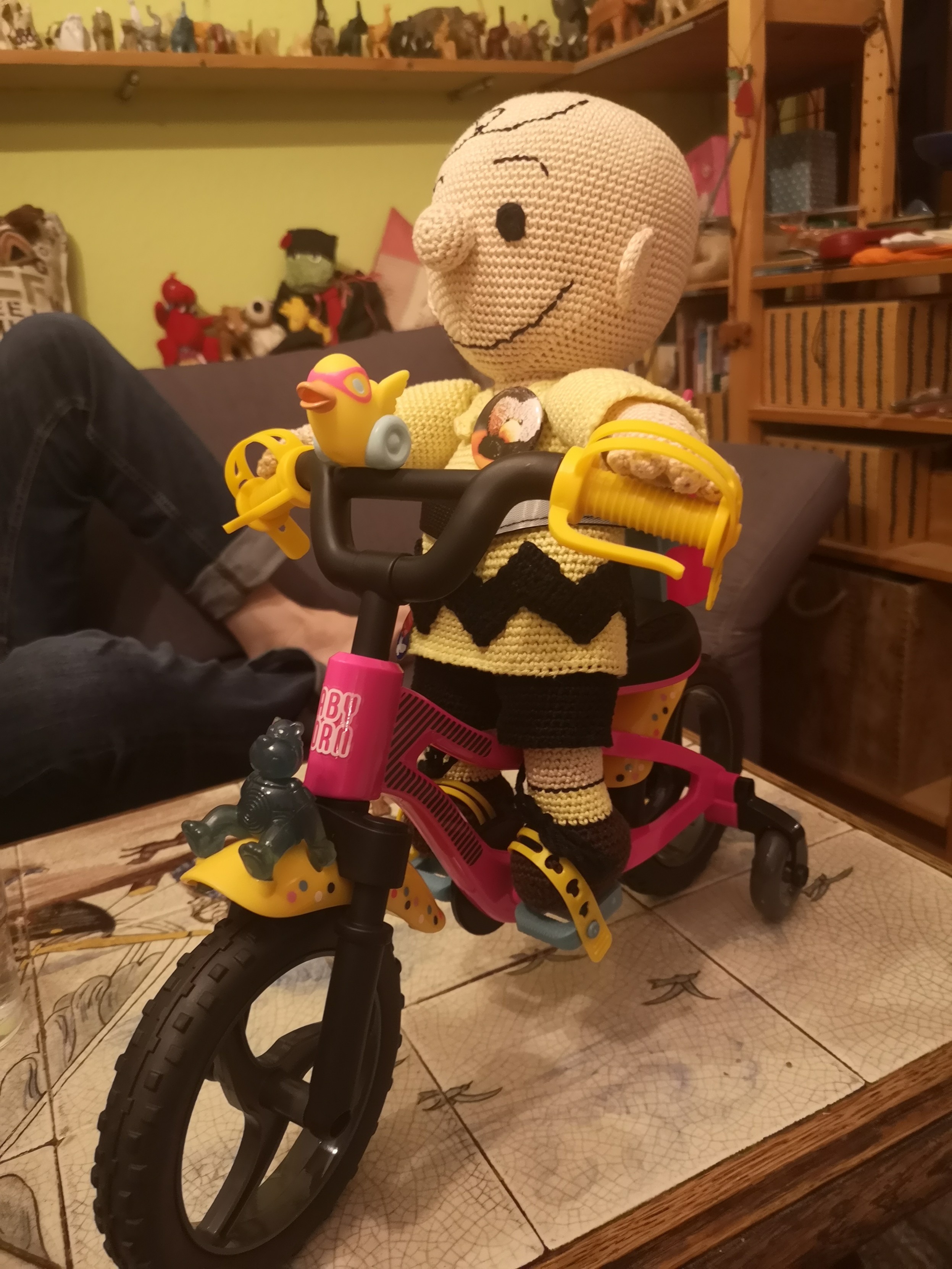 Ein gehäkelter Charlie Brown sitzt auf einem Puppenfahrrad