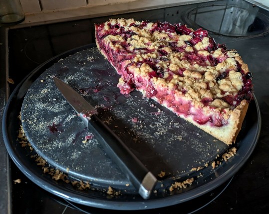 ein angeschnittener Kuchen mit Zwetschgen und Streuseln oben drauf