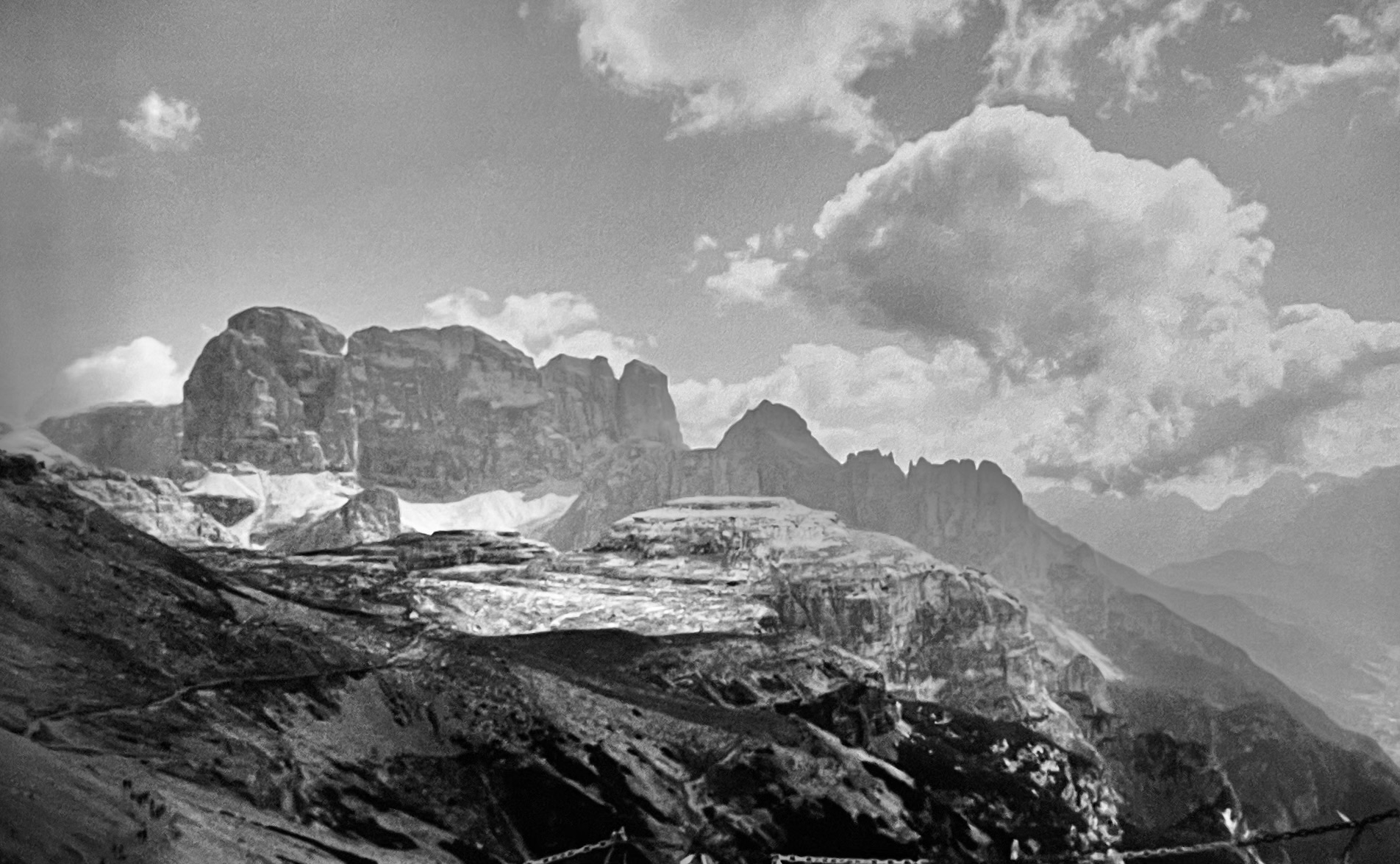 Ein breites steinernes Bergmassiv. Am Schönwetterhimmel sind einige Weiß graue Wolken Ein breites steinernes Bergmassiv. Am Schönwetterhimmel sind einige Weiß graue Wolken