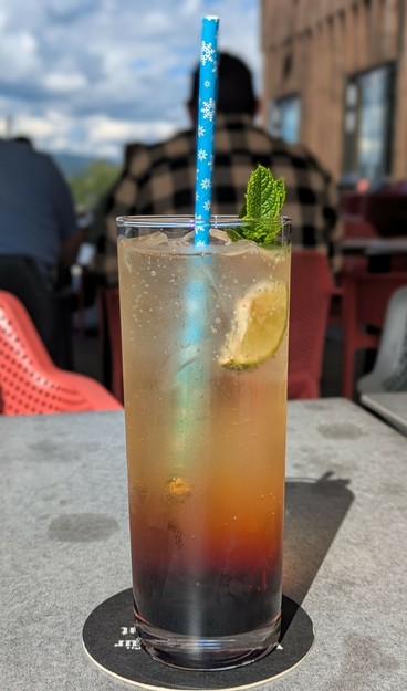 ein Glas mit Strohhalm in dem das Getränk von oben nach unten immer dunkler wird. Sonne.