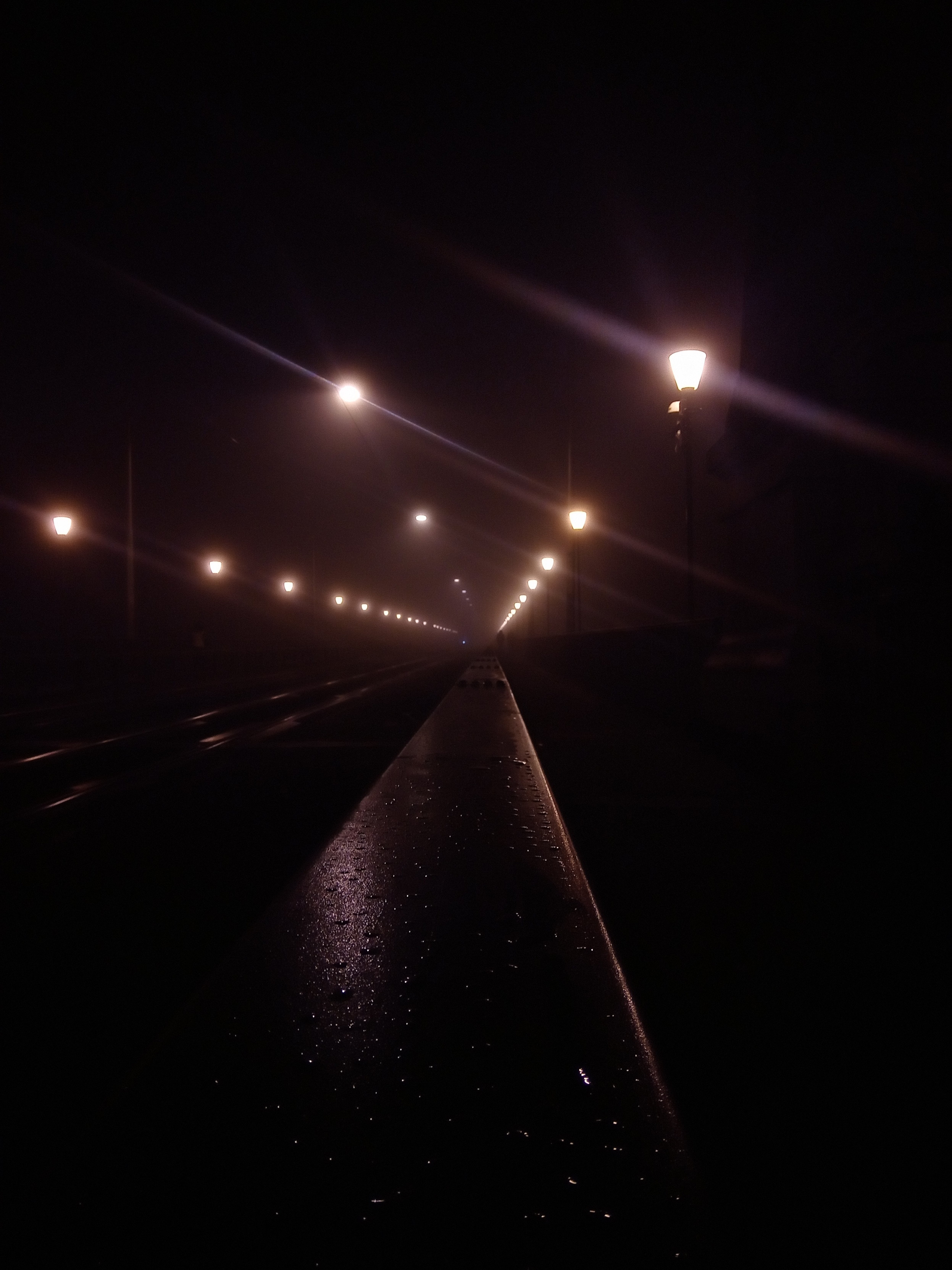 Das Bild zeigt eine Leitplanke auf einer brücke in einem nebelnassen Zustand. Links Von der Leitplanke sind Strassenbahn Gleise zu erkennen. Rechts neben der Leitplanke ist ein Brückengeländer zu erkennen. Oben im bild sind die Strassenlaternen alle schön in drei linien aufgereit. In den Wassertropfen des Nebels spiegelt sich das Licht der Strassenlaternen. Alle linien führen zu einem zentralen punkt. Das Bild zeigt eine Leitplanke auf einer brücke in einem nebelnassen Zustand. Links Von der Leitplanke sind Strassenbahn Gleise zu erkennen. Rechts neben der Leitplanke ist ein Brückengeländer zu erkennen. Oben im bild sind die Strassenlaternen alle schön in drei linien aufgereit. In den Wassertropfen des Nebels spiegelt sich das Licht der Strassenlaternen. Alle linien führen zu einem zentralen punkt.