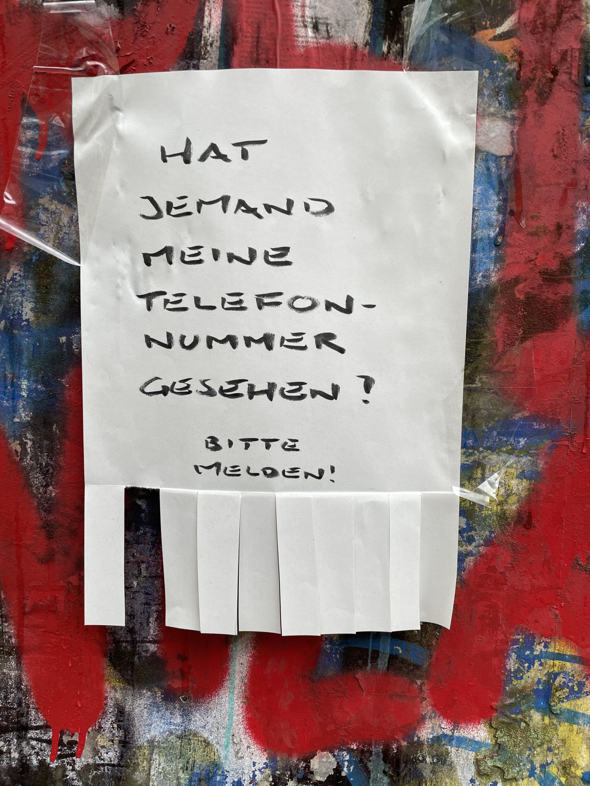 Foto von einem Abreisszettel an einem Stromkasten. Text auf dem Zettel: HAT JEMAND MEINE TELEFONNUMMER GESEHEN? BITTE MELDEN. Die Streifen zum abreißen sind allerdings leer.