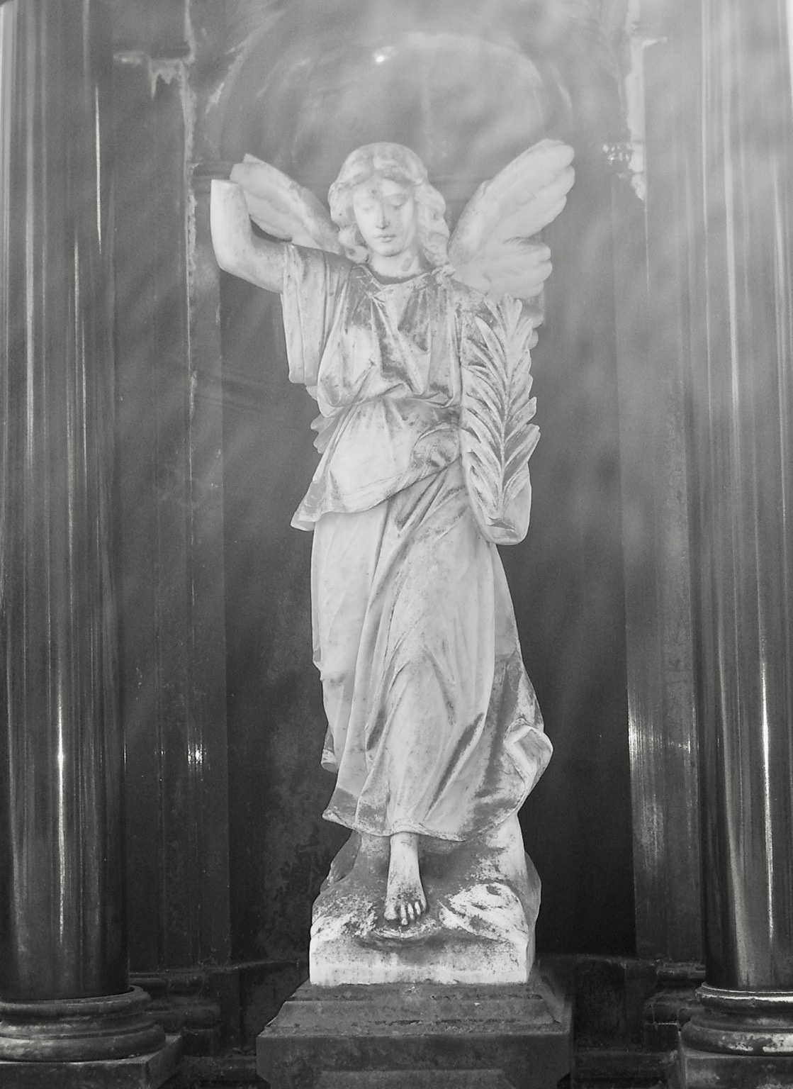 Schwarz-weiß Bild. Die Statue eines weißen Engels in einem schwarzen Tempel – ein Grabmal.