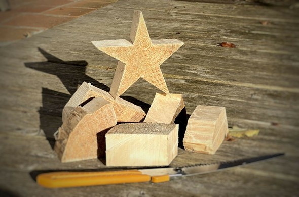 ein Holzstern im weichen Nachmittagslicht steht auf den Holzteilen, die beim Aussägen übrig geblieben sind.