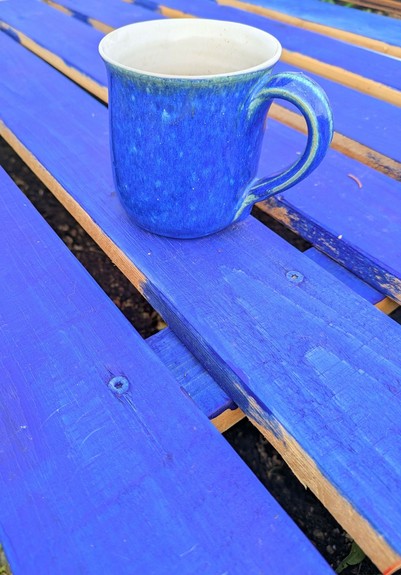eine blaue Tasse steht auf blau gestrichenen Brettern