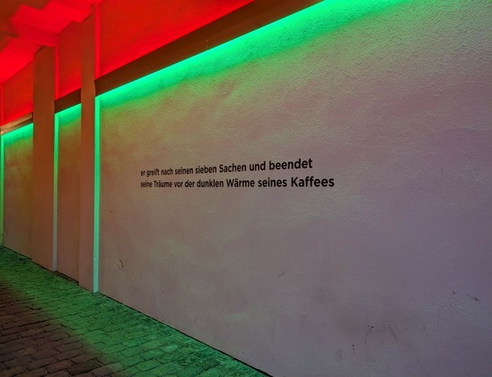 ein Durchgang mit grünem und rotem Licht und einem Spruch an der Wand