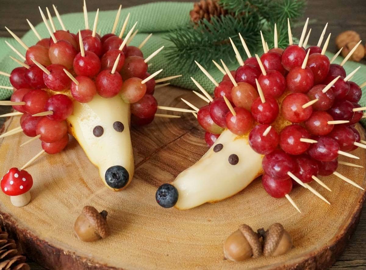 Birnenigel auf Holz: Trauben werden mit Zahnstocher in eine Birne platziert 